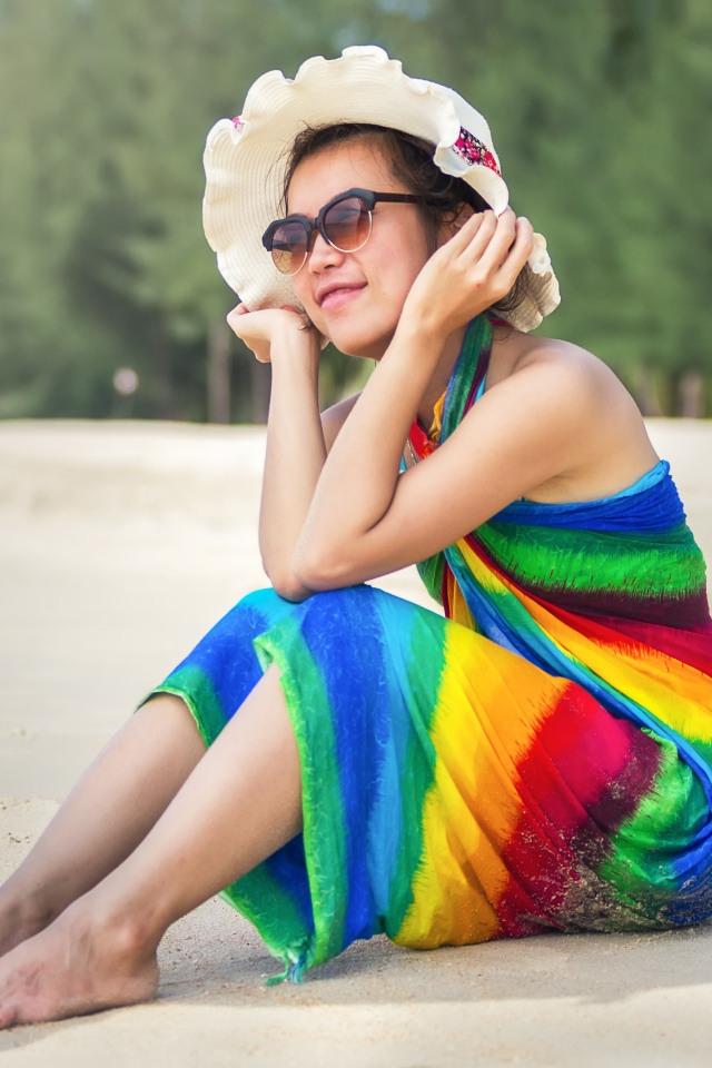 Молодая азиатка сидит на берегу с кокосом