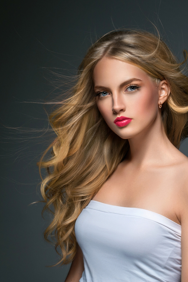 Молодая красивая голубоглазая блондинка на сером фоне