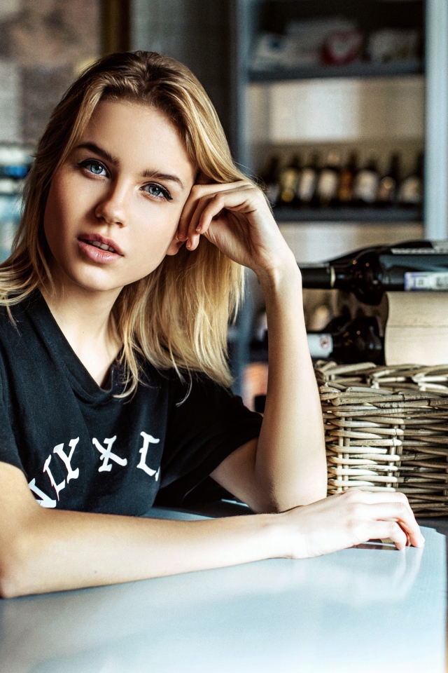 Молодая голубоглазая девушка сидит в кафе