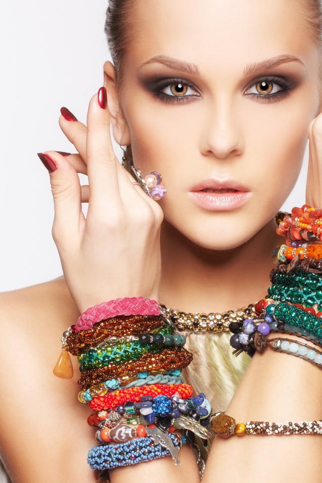 Молодая кареглазая девушка с браслетами на руках на белом фоне