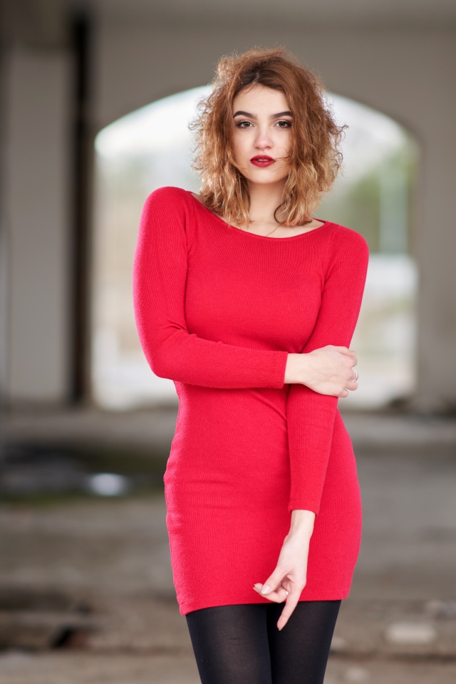 Молодая девушка в красном платье в старом здании