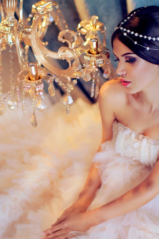 Молодая девушка в белом платье у красивой  люстры
