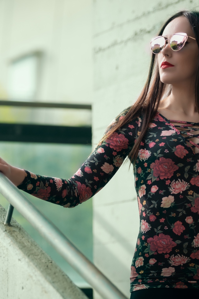 Молодая девушка в солнечных очках стоит на ступеньках