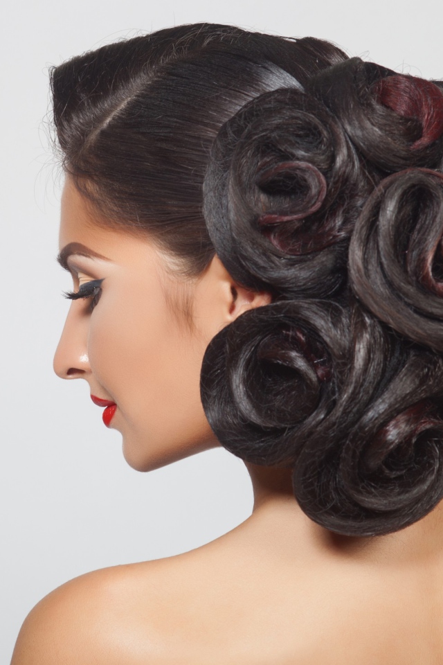 Молодая девушка с красивой прической на сером фоне