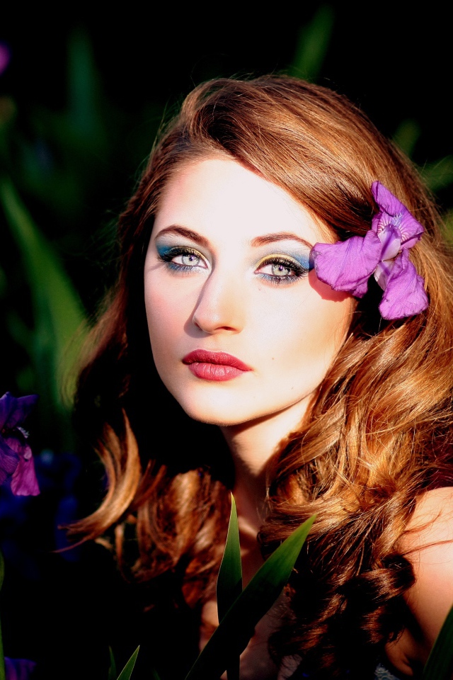 Молодая девушка с фиолетовым цветком ириса в волосах