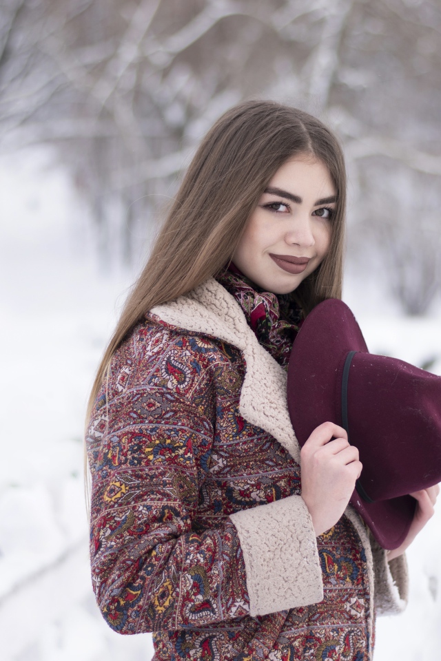 Молодая длинноволосая девушка шатенка с шляпой в руках зимой