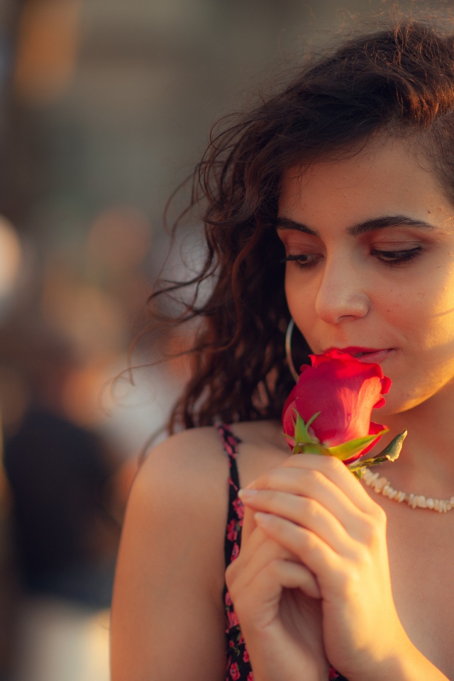 Молодая нежная девушка с красной розой в руке