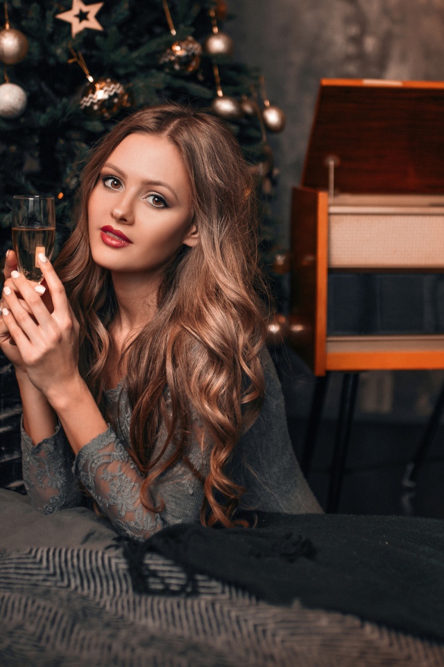 Красивая девушка с фужером шампанского у новогодней елки