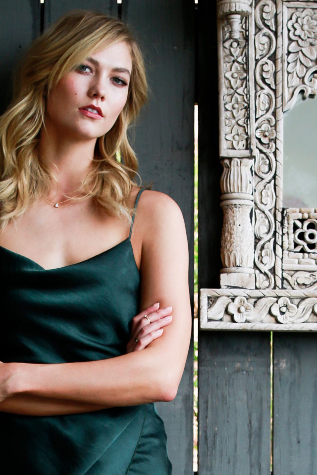 Красивая стильная модель Карли Клосс стоит у стены с зеркалом