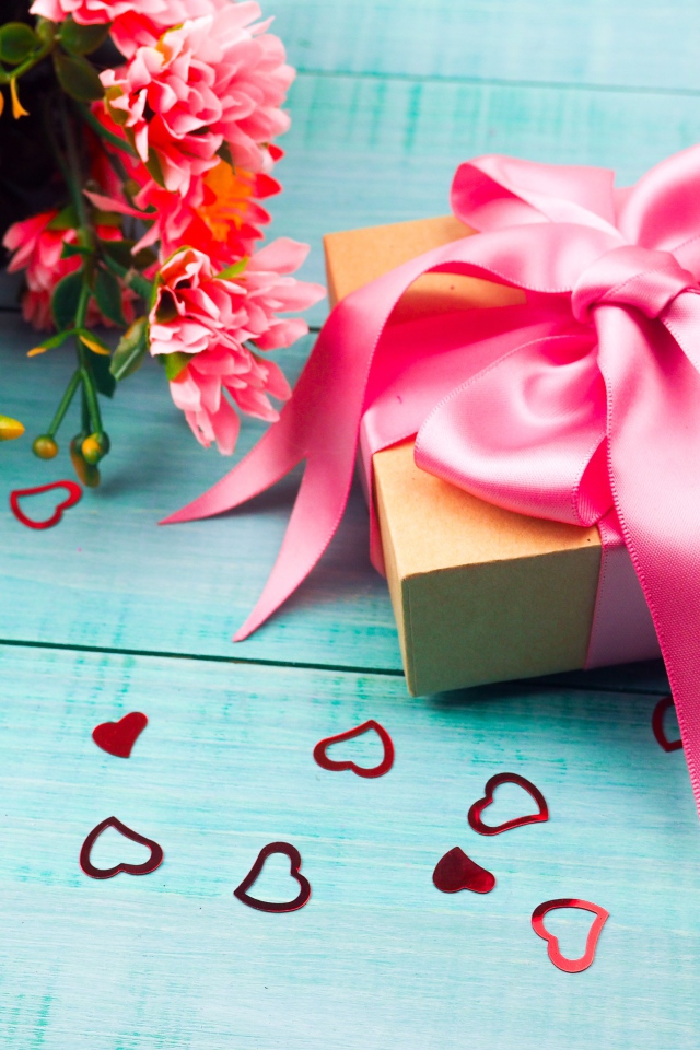 Подарок с розовым бантом на голубом столе с букетом