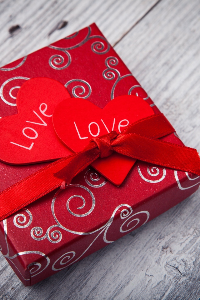 Подарок с красными сердечками на деревянном столе 