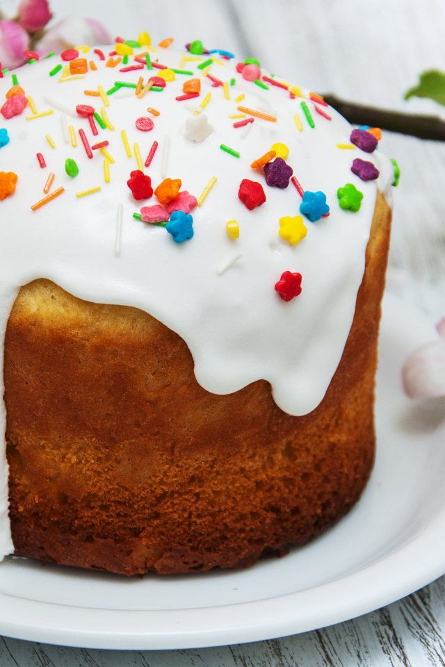 Красивый кулич с белой глазурью на столе с веткой яблони на Великий праздник Пасха