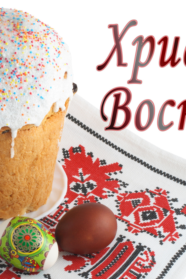 Пасхальный кулич с белой глазурью и крашеными яйцами на рушнике с надписью Христос Воскрес на белом фоне