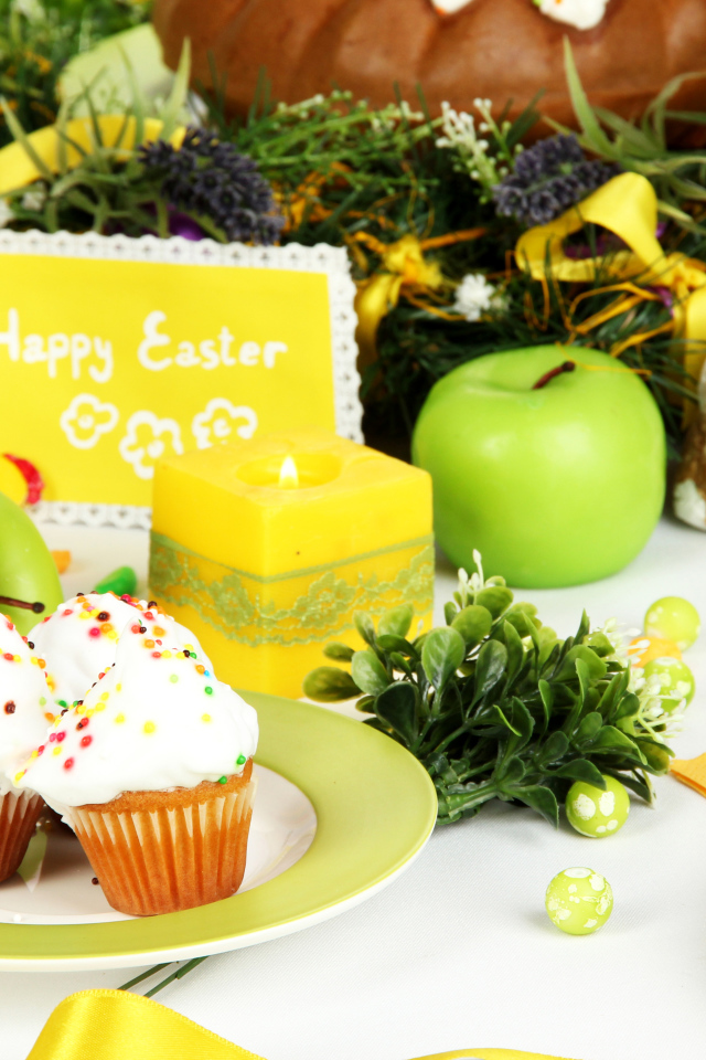 Накрытый пасхальный стол с кексами и зажженной свечой 