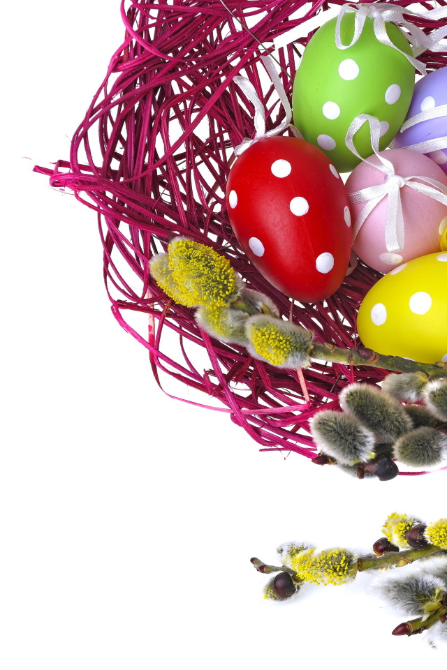 Крашеные пасхальные яйца в гнезде на белом фоне с веткой вербы