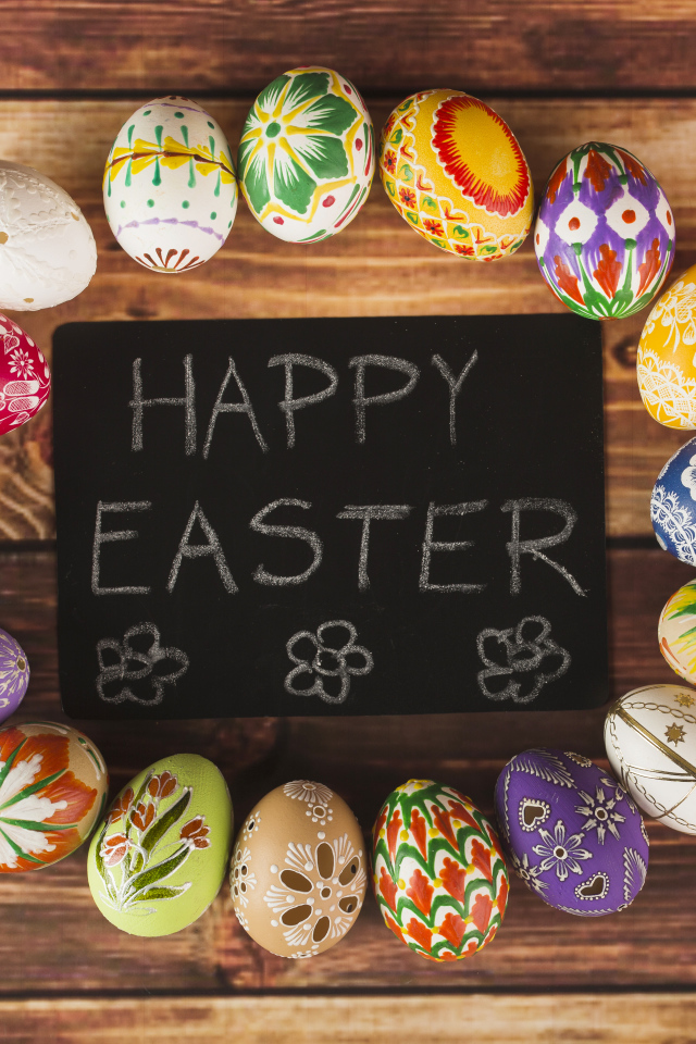 Надпись на английском Счастливой Пасхи на столе с крашеными яйцами