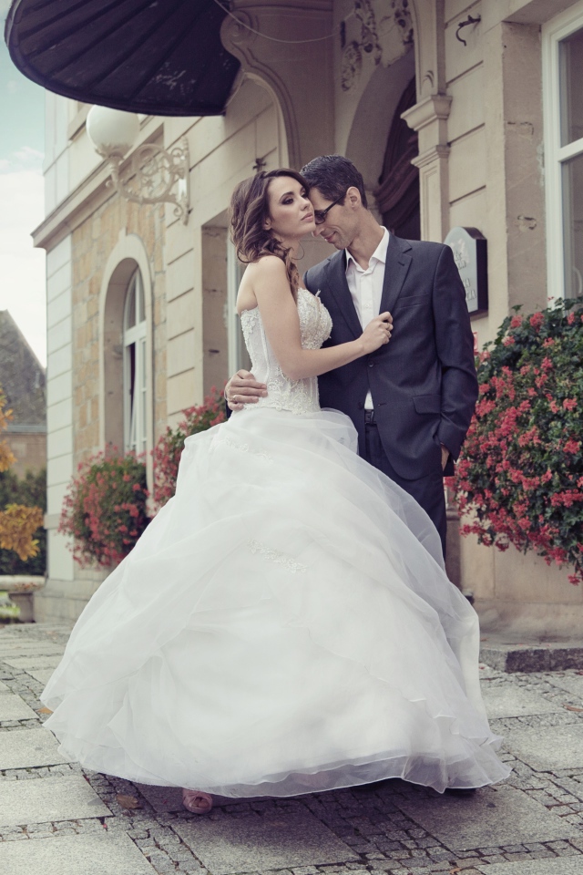 Жених и невеста стоят у здания 