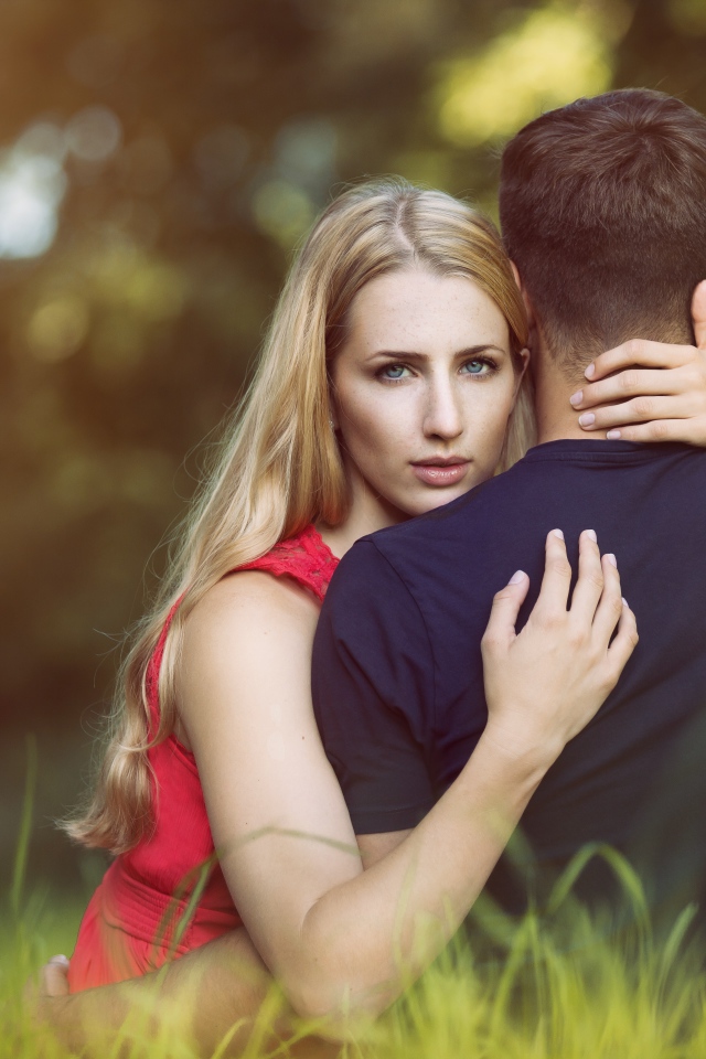 Красивая девушка обнимает парня сидя на траве