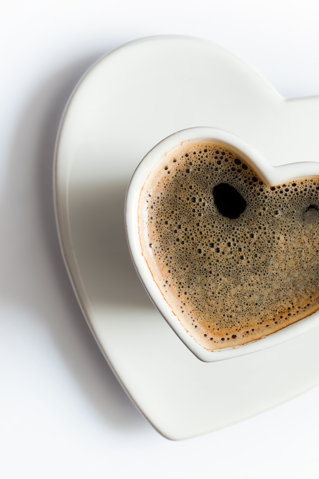 Красивая белая чашка в форме сердца с кофе на белом фоне