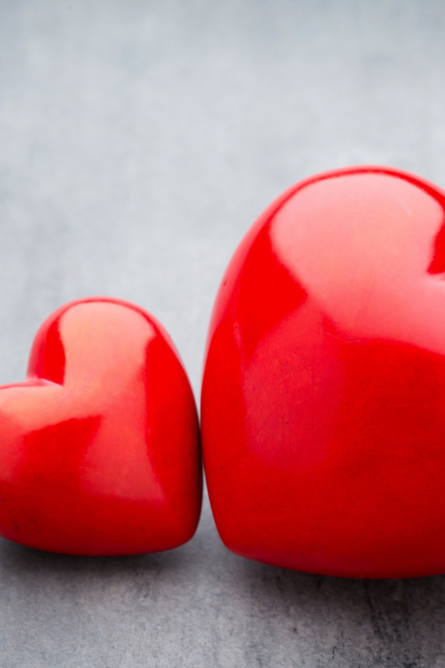 Большое и маленькое красное сердце на сером столе