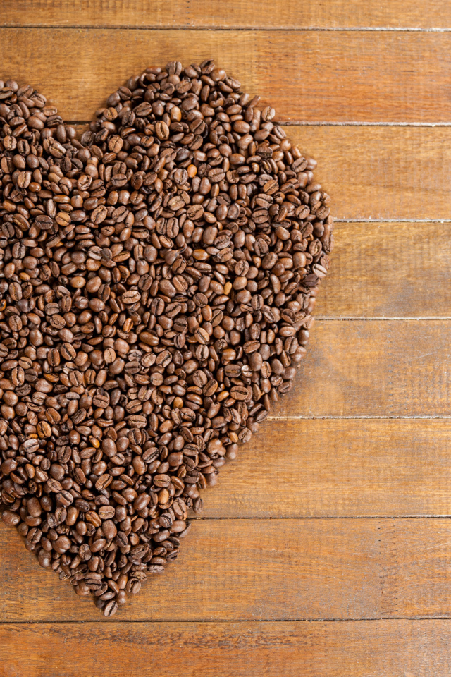 Большое сердце из кофейных зерен на деревянном столе