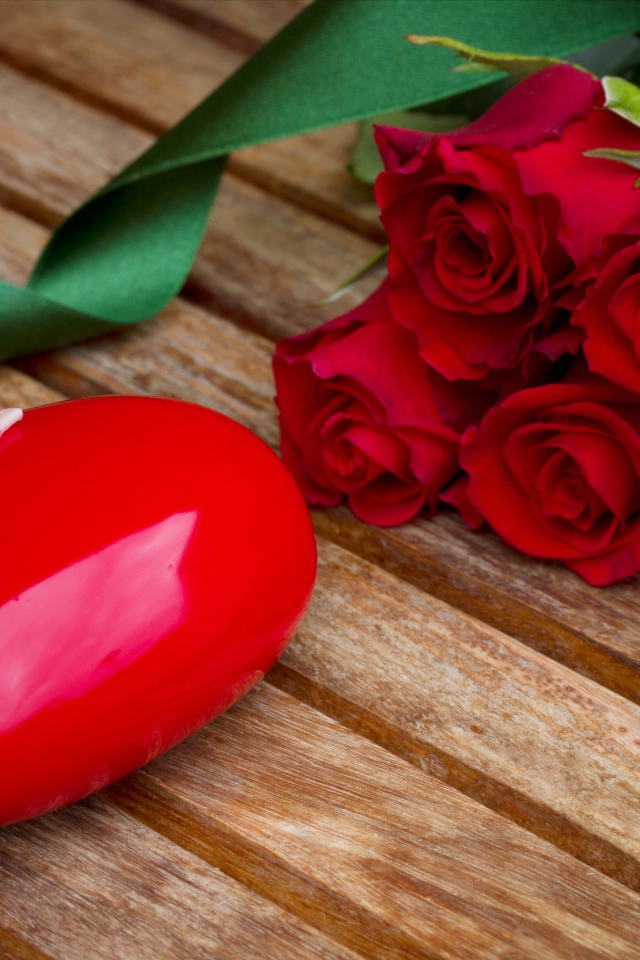 Большое сердце на деревянном столе с букетом красных роз 