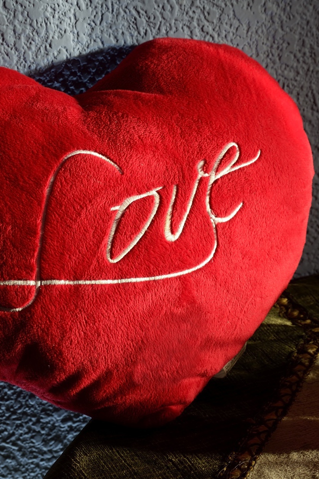 Большое плюшевое красное сердце у стены 