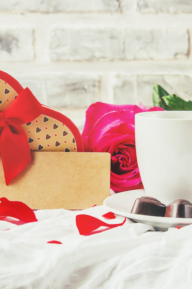 Коробка с подарком на столе с чашкой кофе и красными розами 