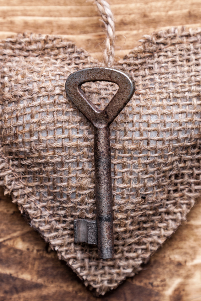Сердечко из мешковины с ключом на деревянном фоне