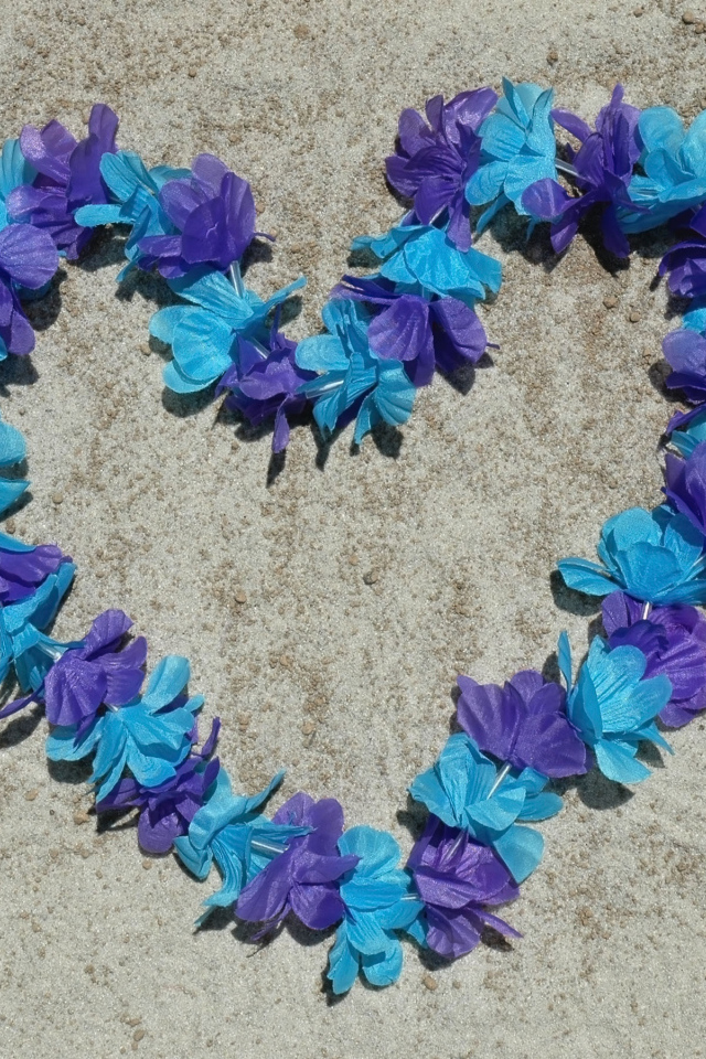 Сердце из цветов на песке на пляже