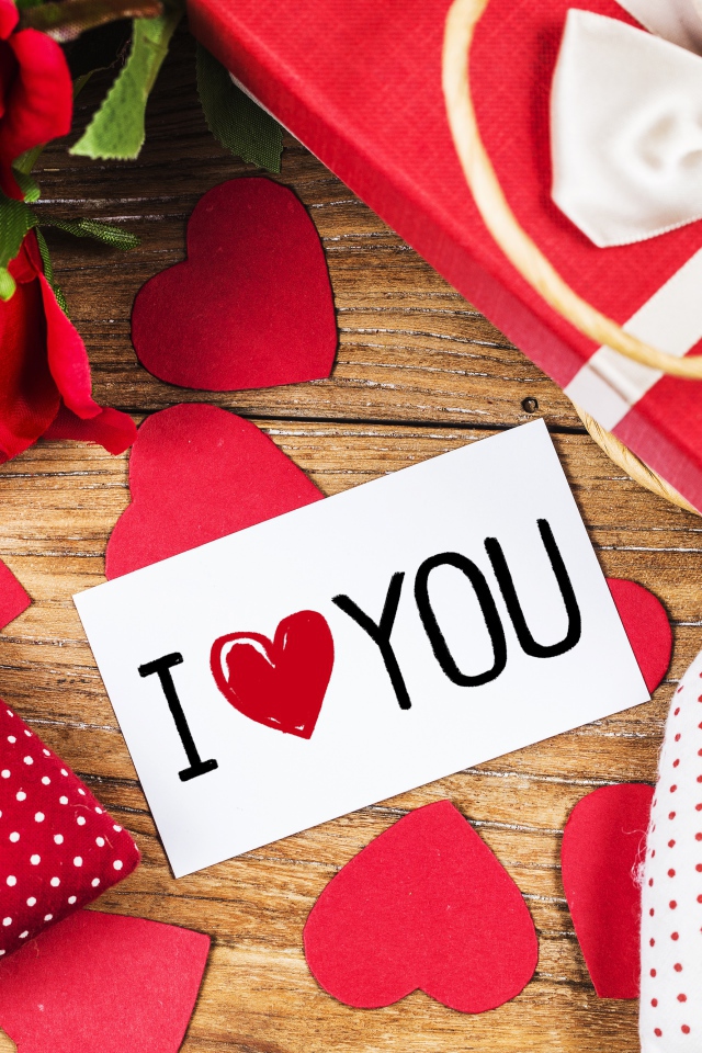 Сердечки, цветы и подарок на столе с запиской