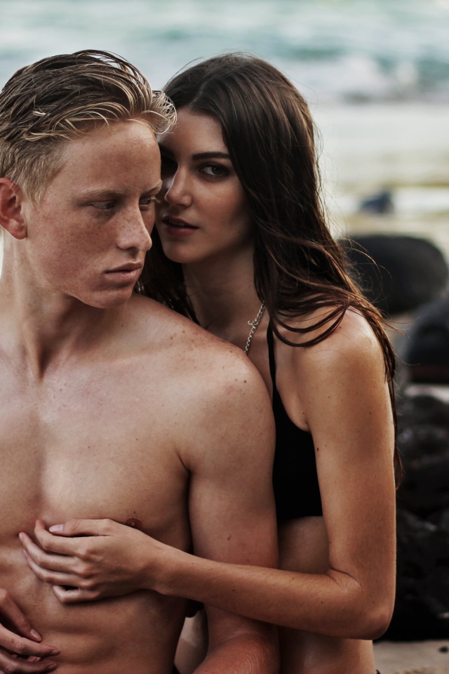 Влюбленная пара сидит на камнях на берегу моря 