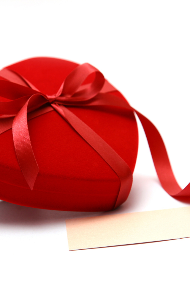 Красная коробка для ювелирных изделий в форме сердца на белом фоне 