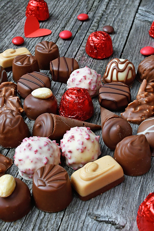 Сладкое сердце из шоколадных конфет на деревянном столе