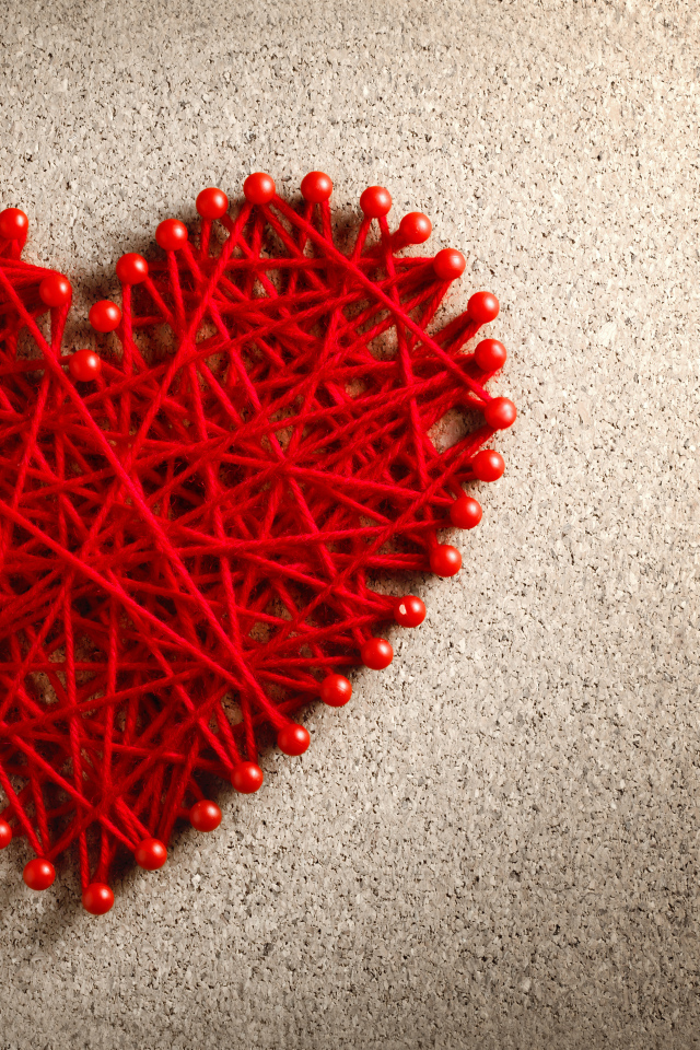 Сердце из красных нитей и невидимок на сером фоне