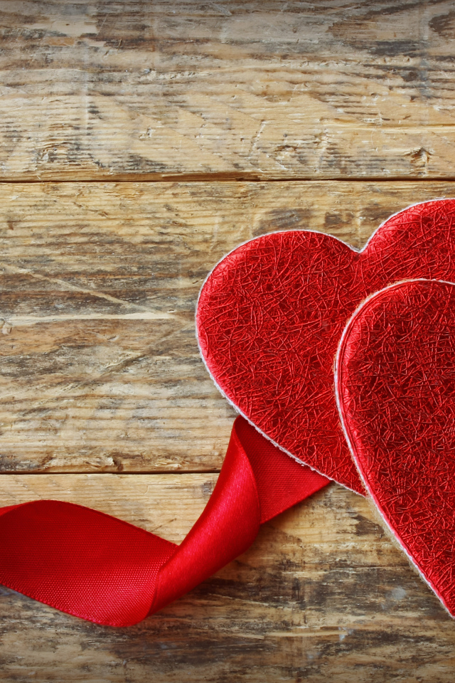 Два сердца с красной лентой на деревянном столе
