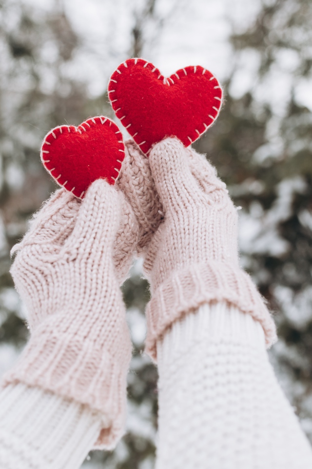 Два красных сердечка из ткани в руках у девушки 