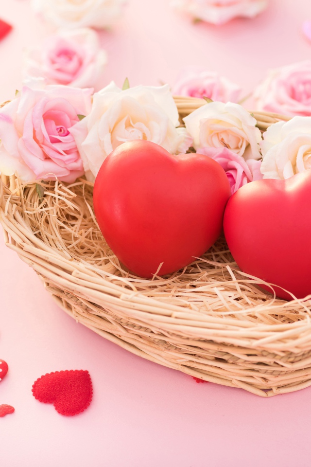 Два красных сердца лежат в корзинке с розами 