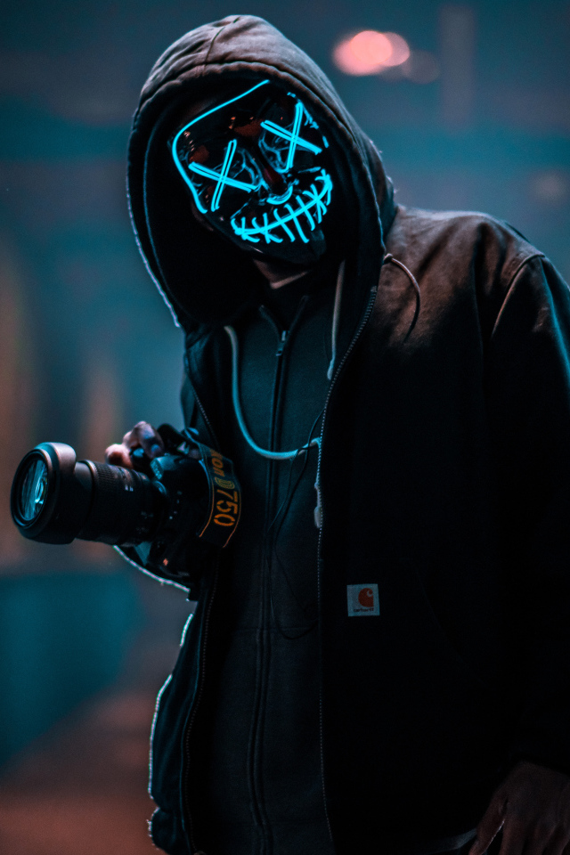 Парень в неоновой маске анонима с фотоаппаратом