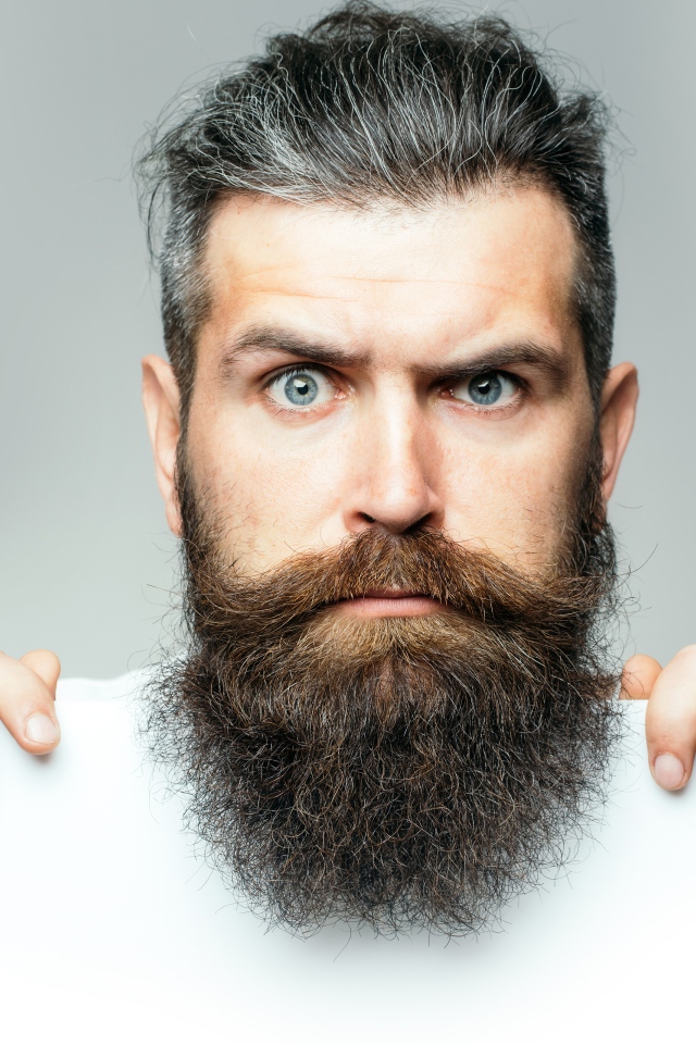 Голубоглазый мужчина с бородой на сером фоне