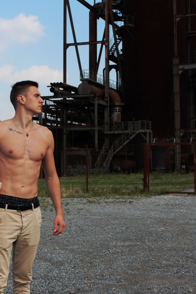 Красивый молодой парень стоит на фоне завода