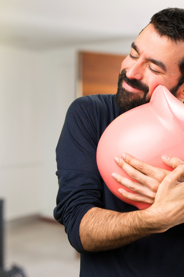 Man hugging a pink pig piggy bank