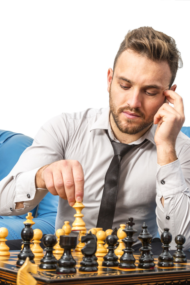 Мужчина играет в шахматы на синем диване