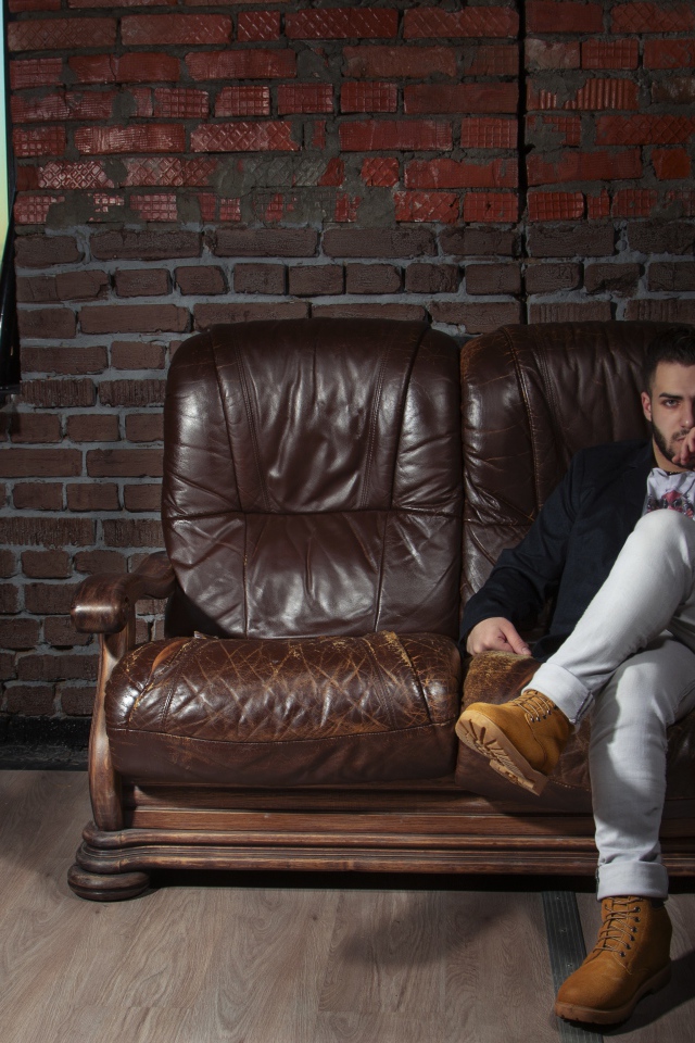 Стильный мужчина сидит в кожаном кресле 