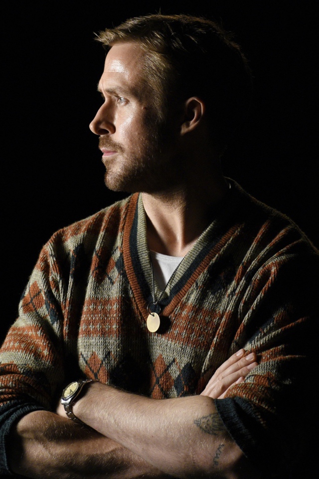 Актер Райан Гослинг в свитере на черном фоне 