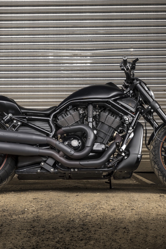 Черный тяжелый мотоцикл Harley-Davidson у гаража