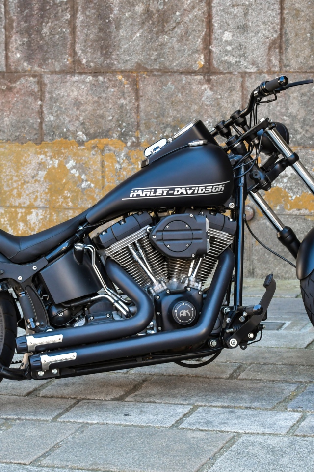 Черный стильный мотоцикл Harley-Davidson на фоне стены