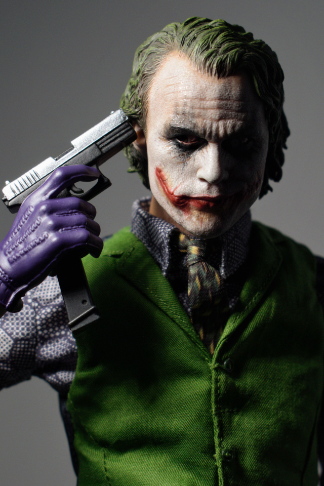 Персонаж Джокер с пистолетом в руке на сером фоне
