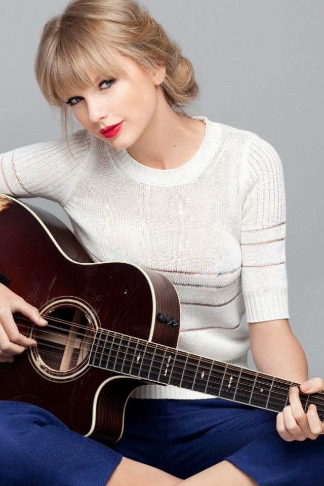 Красивая певица Тейлор Свифт с гитарой на сером фоне