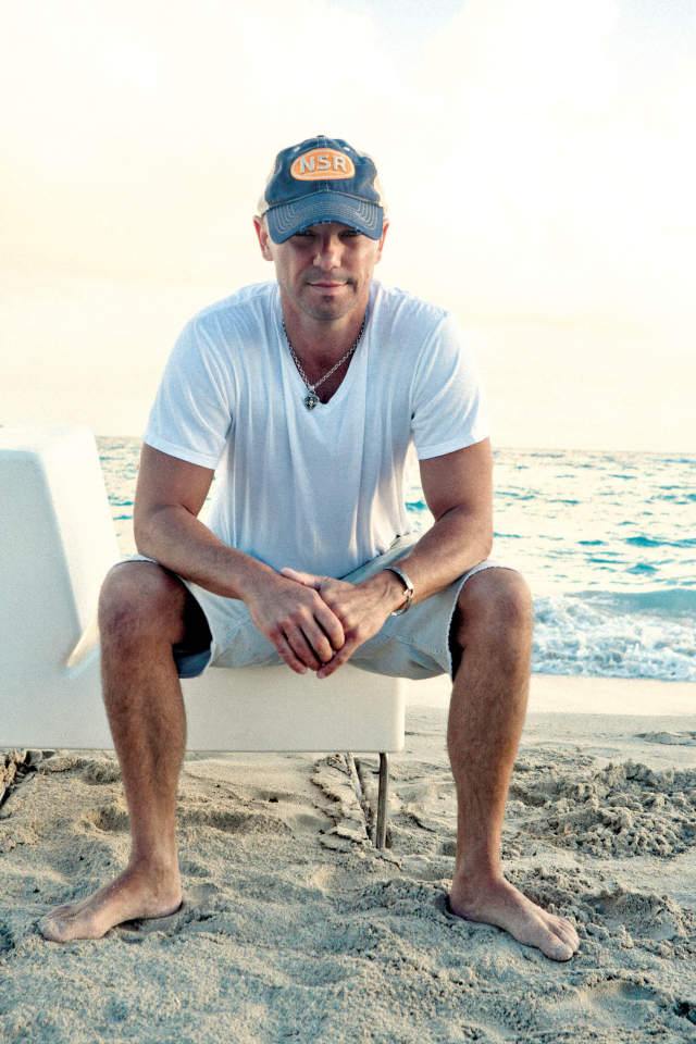 Исполнитель кантри Кенни Чесни на белом кресле на пляже